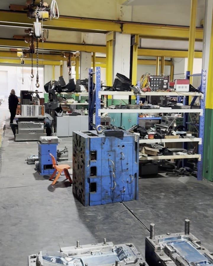 Steel injection molds and mold blocks on the floor of a Chinese mold-making shop with overhead crane