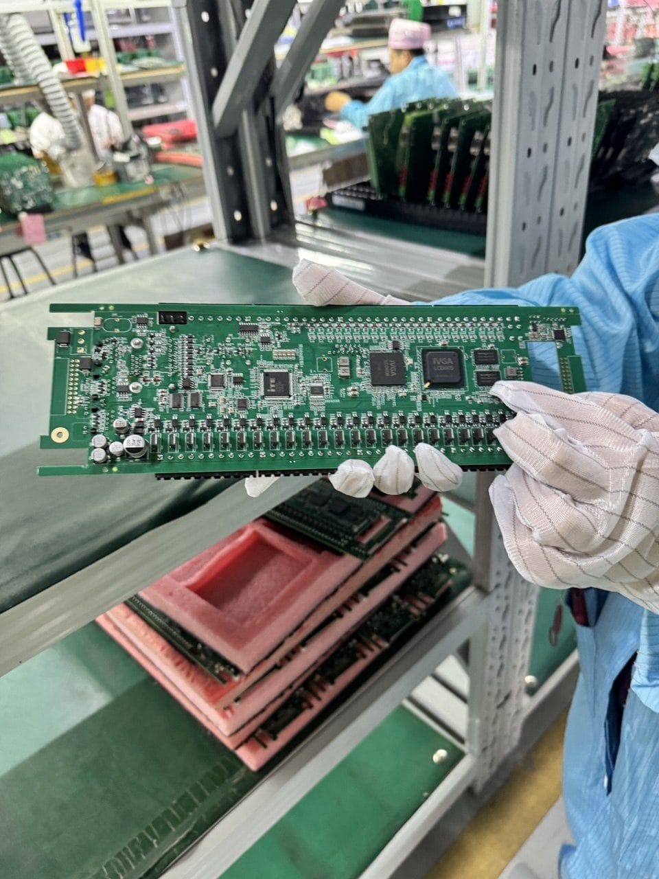 A long, fully populated control board held over ESD trays