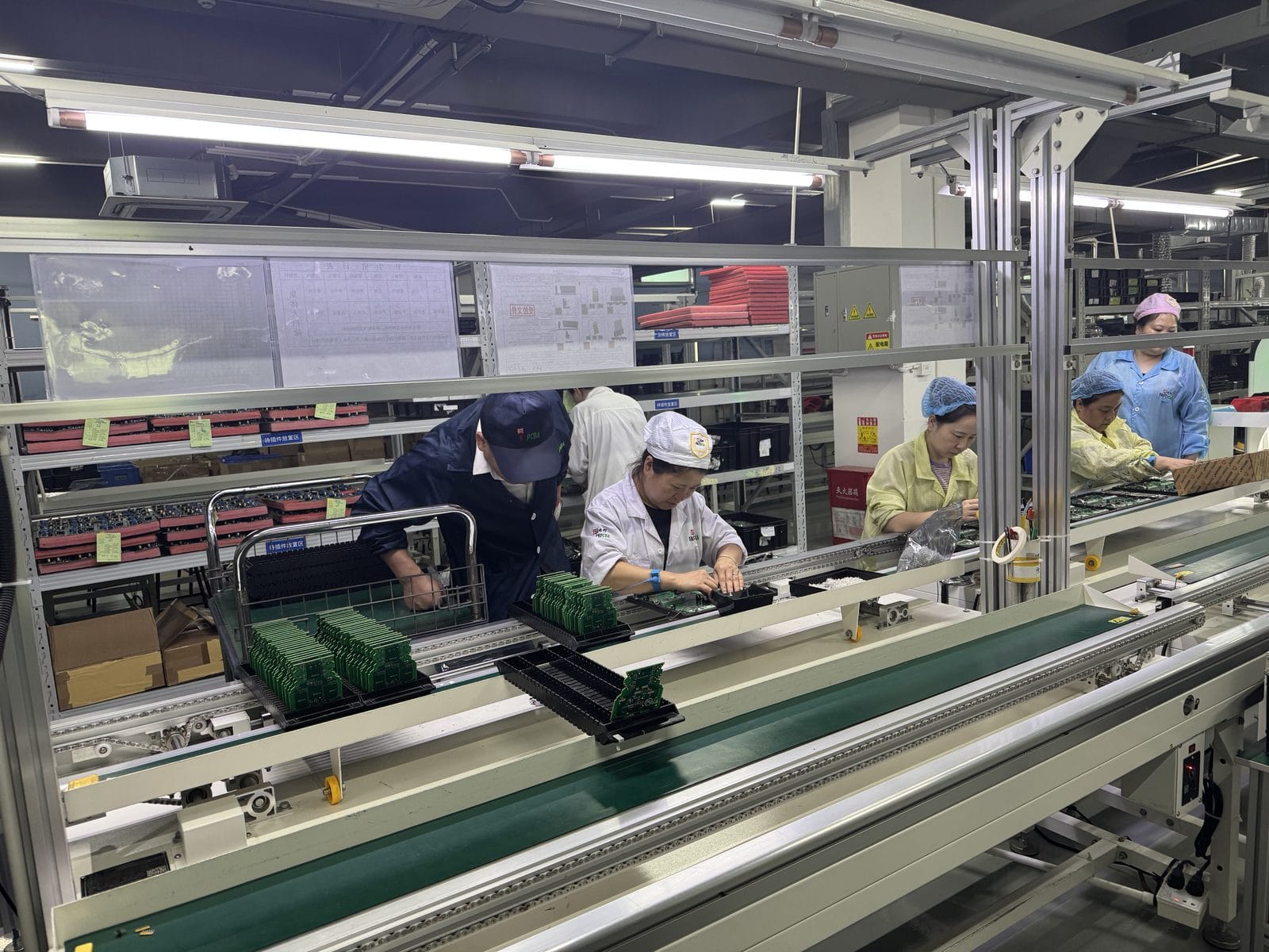A live SMT assembly line with operators placing boards into magazine racks