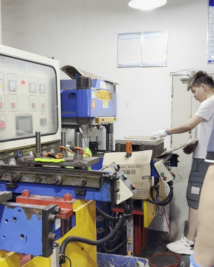 Worker loading a silicone molding press in a Chinese factory